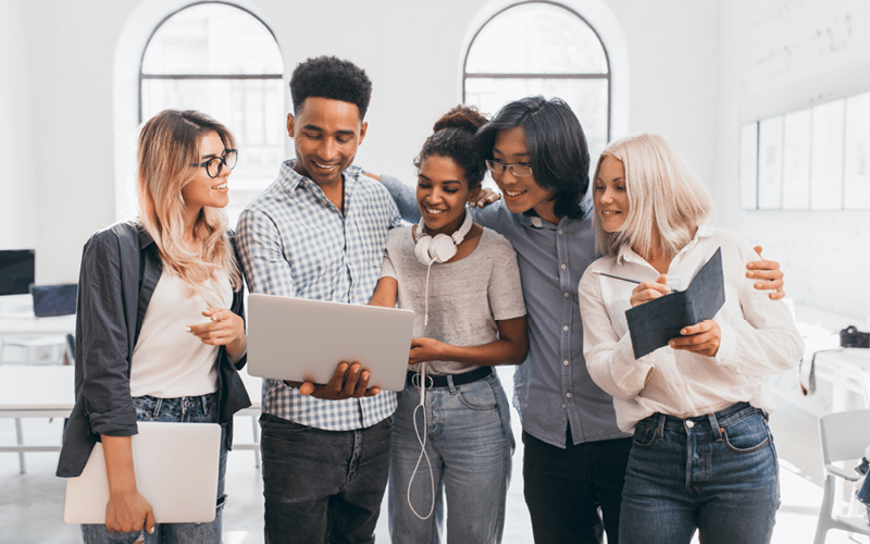 A imagem mostra um grupo de profissionais diversos, observando um mesmo material, que está ao centro. A imagem busca representar, de forma lúdica, a mudança para um mindset digital.