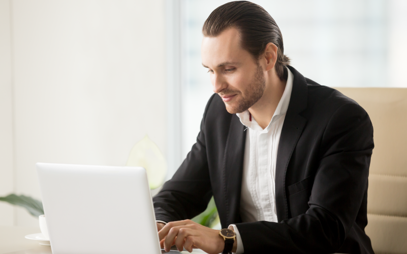 A imagem mostra um homem em roupas sociais utilizando o computador. Ela busca representar como funciona o executive search.