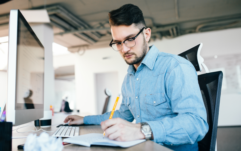 A imagem mostra um homem fazendo anotações em um caderno. A imagem busca representar, de forma lúdica, como usar big data no RH e quais são os benefícios.