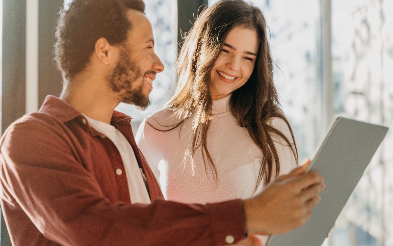 A imagem mostra dois jovens conversando felizes. Ela busca representar a importância das soft skills no ambiente de trabalho e de entender o que são habilidades comportamentais.