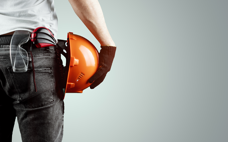 Imagem parcial de homem segurando capacete. A imagem representa a mão de obra temporária para atender a uma demanda complementar de serviços.