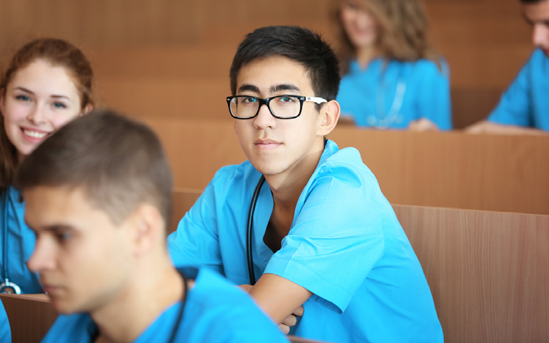 Na imagem, vemos estudantes com vestes azuis da área da saúde.