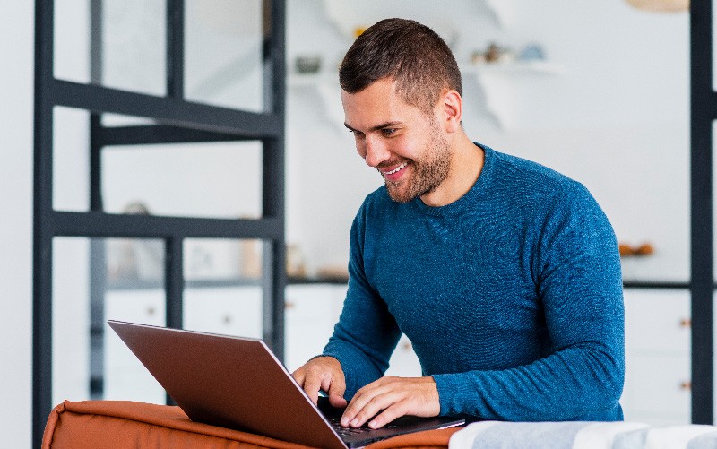 A imagem mostra uma homem utilizando o notebook e sorrindo. A imagem busca representar o RH 4.0 de forma lúdica.