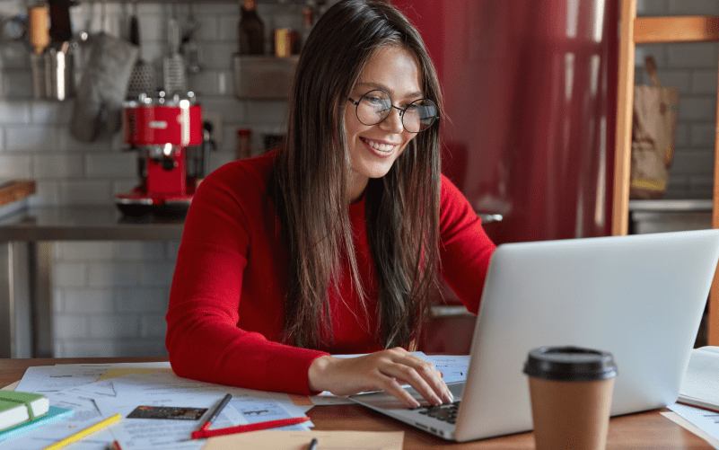 A imagem mostra uma mulher sorrindo enquanto mexe em um notebook e pesquisa sobre como fazer recrutamento inteligente.