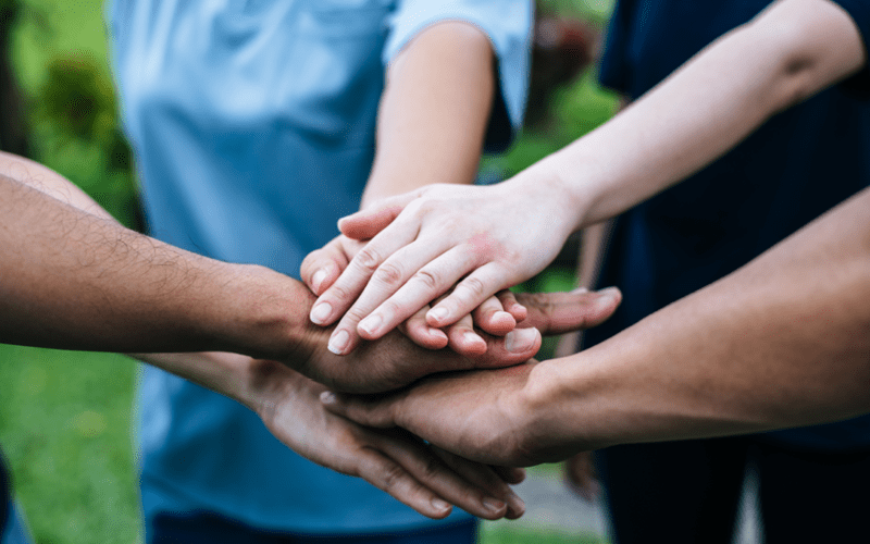 Na imagem, vemos mão unidades ao centro, uma sobrepondo a outra. Ela busca representar a união que existe entre colaboradores de uma empresa com boa cultura organizacional e que motiva o engajamento das equipes.