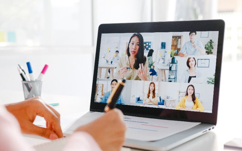 A imagem está focada em uma tela de notebook, que mostra seis pessoas que estão participando, juntas, de uma reunião online. Elas estão conversando e planejando as melhores formas de selecionar trainees e estagiários.