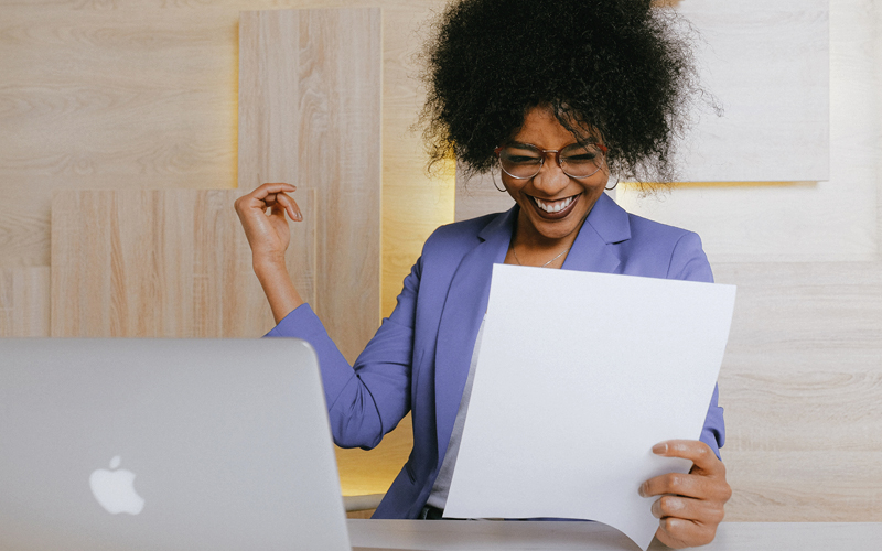 A imagem mostra uma mulher negra trabalhando. Ela está feliz e animada com as tarefas que executa, demonstrando, de forma lúdica, o que é vivenciar o estado de flow no trabalho.
