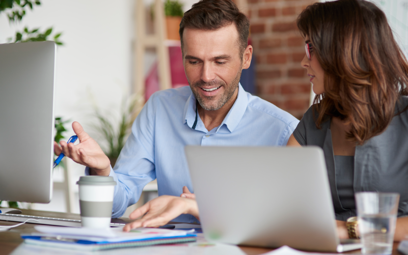 A imagem mostra um homem e uma mulher em um ambiente de trabalho informal. Eles estão conversando sobre as principais tendências em RH para 2022.