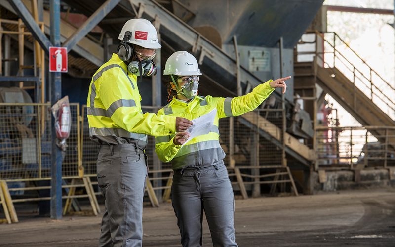 Dois trainees (um homem e uma mulher) trabalhando na área industrial.