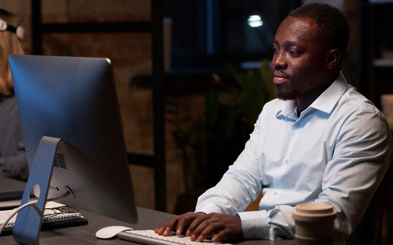 Homem negro pesquisando em um computador sobre boas práticas para fazer uma melhor gestão comportamental na empresa onde trabalha.