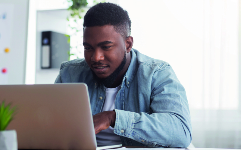 Homem jovem e negro pesquisando em um notebook sobre boas práticas para criar uma boa página de carreira para sua empresa.