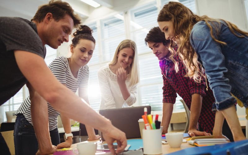 Grupo de pessoas reunidas desenvolvendo um novo projeto. Elas retratam como deve ser um trabalho em equipe bem liderado de uma empresa.