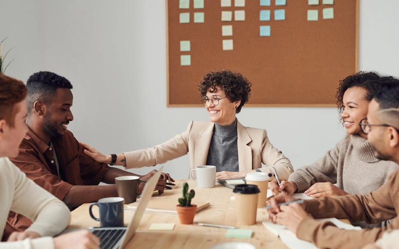 A imagem mostra um grupo de profissionais sentados ao redor de uma mesa. Ela busca representar um diálogo sobre transformação cultural nas empresas.