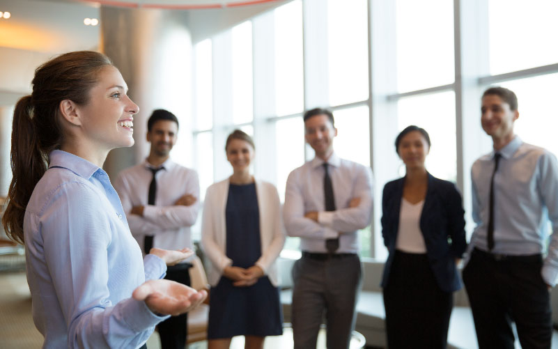 Grupo de profissionais em pé conversando em uma sala de reuniões. Eles sorriem e estão tranquilos, representando uma gestão humanizada.