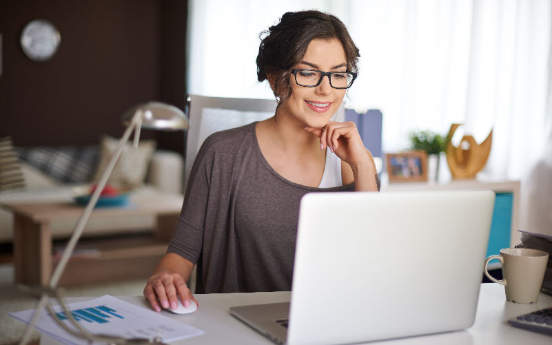 Imagem de mulher com cabelos curtos e óculos utilizando um notebook. Ela está em um ambiente de escritório e a imagem busca representar a estruturação de um organograma empresarial.
