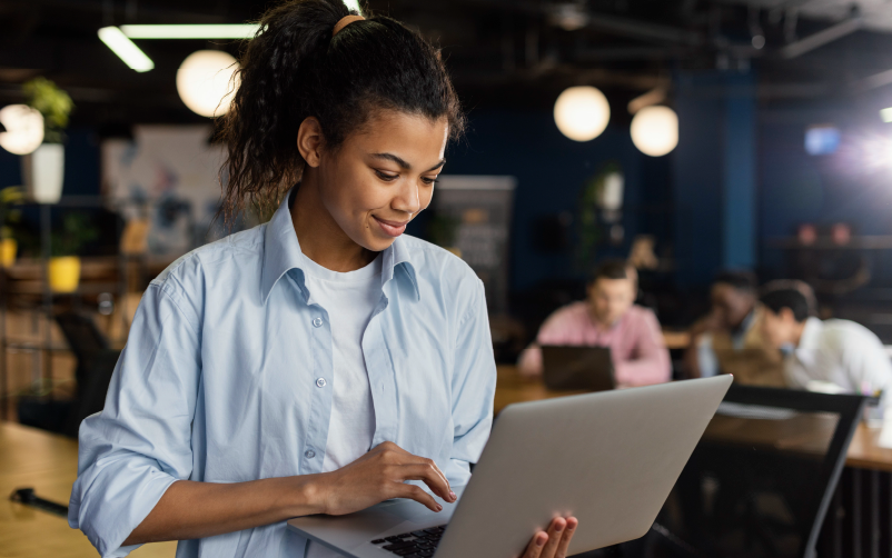 Imagem de mulher com roupas descontraídas, sentada de forma despojada usando um notebook. O objetivo é demonstrar como acontece o processo de desenvolvimento das power skills.