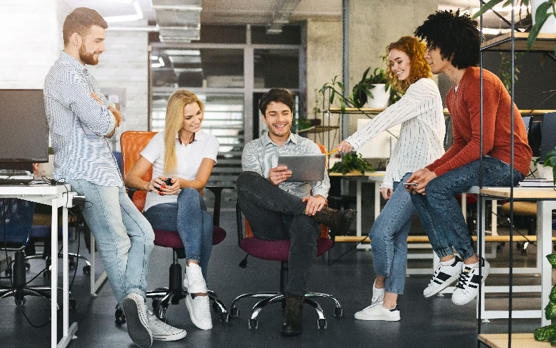 Grupo de profissionais conversando em um escritório, de modo descontraído. A imagem busca representar a importância de valorizar e desenvolver o capital intelectual nas empresas.