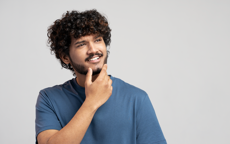 Imagem com fundo liso branco e homem em destaque. Ele está pensativo e esboça um sorriso, buscando representar a heutagogia no aprendizado.