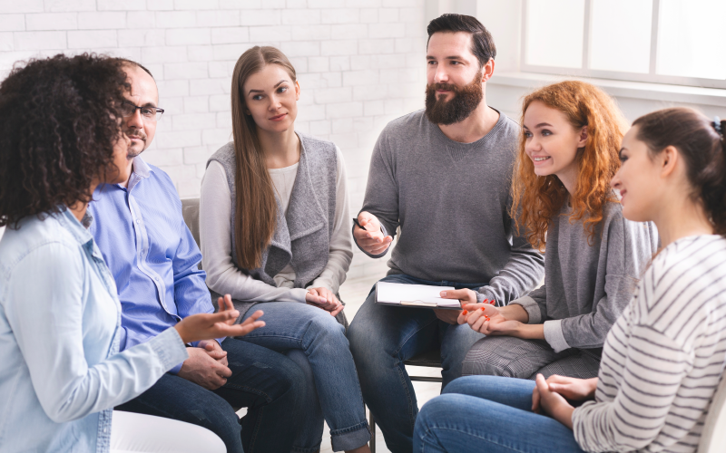 Grupo de profissionais reunidos em círculo, como em uma roda de conversa. O objetivo da imagem é representar uma das ações de Janeiro Branco que o RH pode realizar.