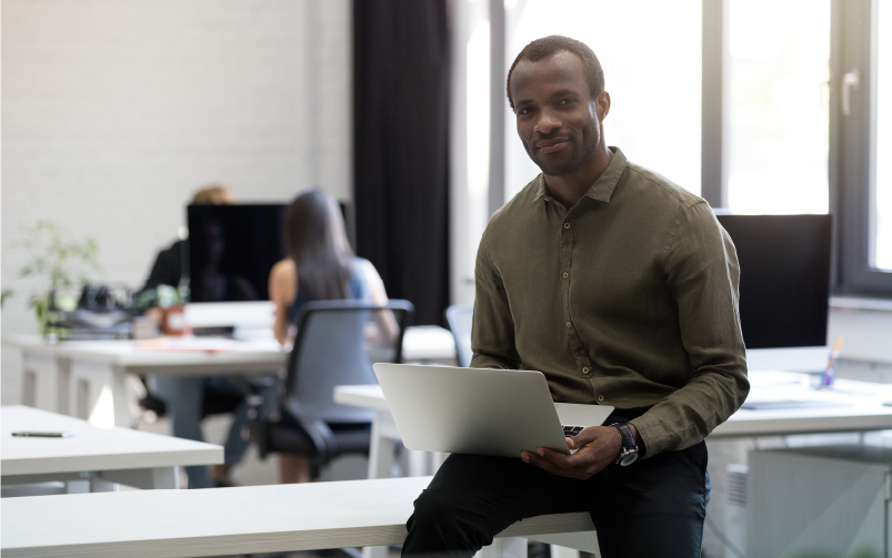 Homem sentado em uma mesa de escritório com notebook no colo. A imagem busca representar a análise dos indicadores de uma empresa em busca do turnover ideal.