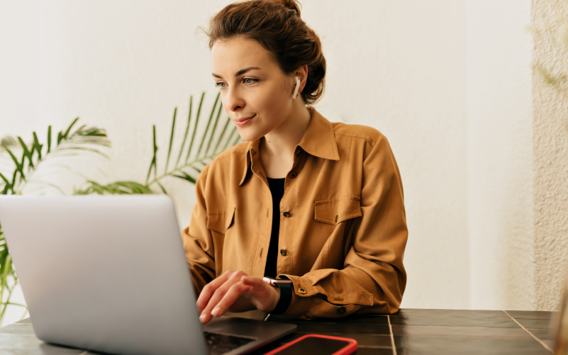 Mulher jovem com fones de ouvido mexendo em um notebook representando um processo de recrutamento no linkedin