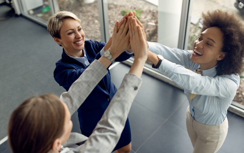 Equipe comemorando os resultados de um projeto, que foi bem executado graças a confiança no trabalho que todos os membros tiveram uns nos outros.