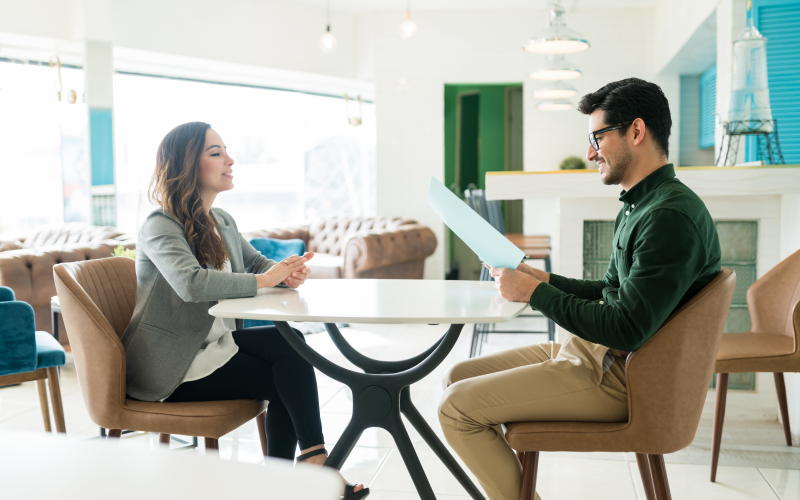 Imagem de capa para blog post. Na foto, observa-se duas pessoas, sendo um homem e uma mulher. O homem segura um documento enquanto ambos conversam. O título do artigo para o blog é "Descubra como contratar um headhunter em 6 passos".