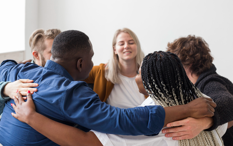 Imagem de capa de post blog sobre recrutamento inclusivo, com foco em levar mais diversidade para as empresas. Na foto, temos um grupo de pessoas, levemente abraçadas, em círculo.