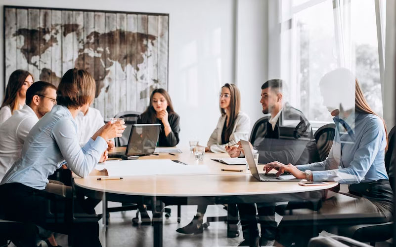 Imagem de capa para blog, no qual aborda dicas para um planejamento de RH efetivo. A imagem traz um grupo de profissionais reunidos no planejamento de novas demandas. Eles estão juntos, sentados ao redor de uma mesa circular, com notebooks e materiais de escritório auxiliares.