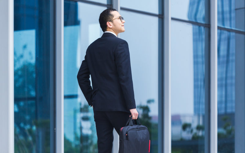 Imagem de capa de post blog sobre retenção de executivos nas empresas. Na foto, observa-se um jovem executivo olhando para uma nova empresa. Ele veste roupas formais e dá a sensação de estar vislumbrando oportunidades profissionais promissoras.