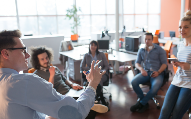 Imagem de capa de blog post sobre estratégias de liderança. Na foto, há um grupo de pessoas conversando em um ambiente corporativo.