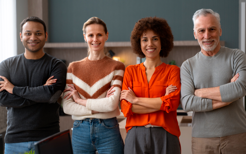 Imagem de capa para blog post sobre dia do profissional de RH. Quatro profissionais sorridentes de diferentes idades e perfis, com os braços cruzados, simbolizando diversidade, confiança e trabalho em equipe.